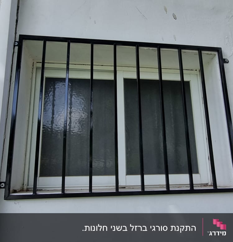 חלון עם סורגים שחורים על קיר לבן